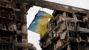 Eine zerrissene ukrainische Flagge hängt an einem Draht vor einem Wohnhaus, das während des ukrainisch-russischen Konflikts in der südlichen Hafenstadt Mariupol (Ukraine) am 14. April 2022 zerstört wurde. | REUTERS