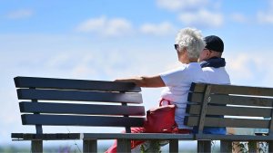 Eine ältere Frau und ein älterer Mann sitzen auf einer Bank in der Sonne. | picture alliance / SvenSimon