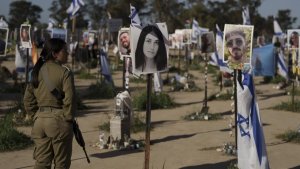 Eine israelische Soldatin steht neben Fotos von Menschen, die beim Terrorangriff der Hamas am 7. Oktober 2023 getötet wurden. | AP