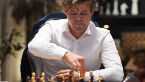 Magnus Carlsen sitzt vor einem Schachbrett. | dpa