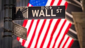 Wall Street Straßenschild vor einer amerikanischen Flagge. | picture alliance/dpa/AP