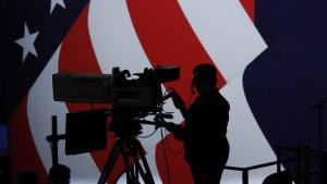 Schemenhaft ist der schwarze Umriss eines Kameramanns vor der amerikanischen Flagge zu sehen. | AP